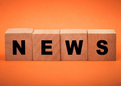 Stock image of blocks that spell out the word news on an orange background
